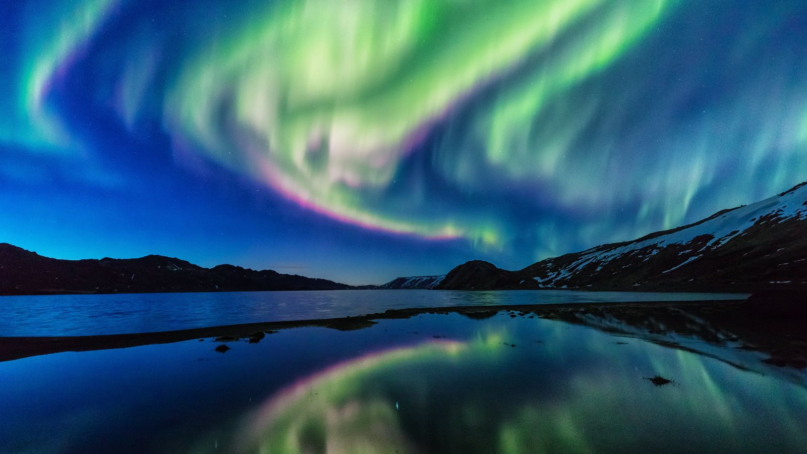 Northern lights in Iceland over a body of water.