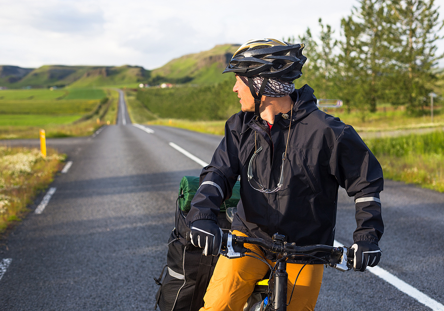 Close-up shot of a biker on the road with mountains in Iceland in the background.