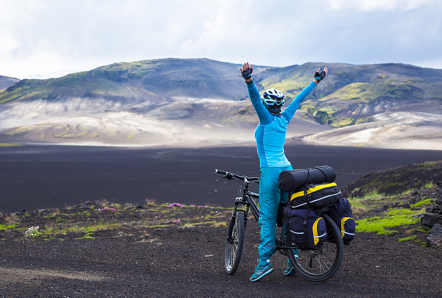 A mountain biker in Iceland with her arms outstretched.