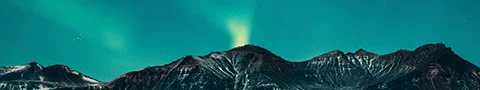 Aurora borealis over a mountain reflecting in a lake.