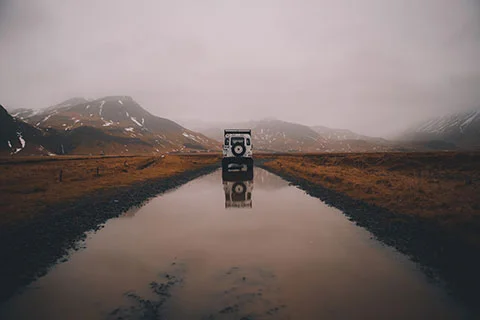 A car reflected in a soaked gravel road